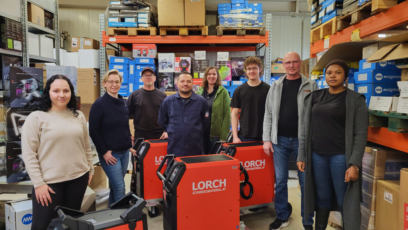 Teamfoto von Schweissmaterial.at mit Lorch Schweißgeräten und Optrel Schweißhelmen im Lager vom Unternehmen Fladenhofer